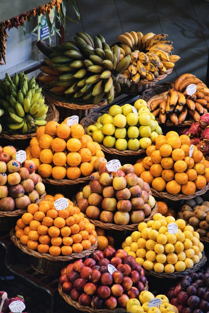 Madeira Aktivurlaub: Highlights für Wanderer, Abenteurer & Naturliebhaber 5 Buntes Obstangebot mit Bananen, Orangen, Äpfeln und exotischen Früchten auf einem Marktstand auf Madeira