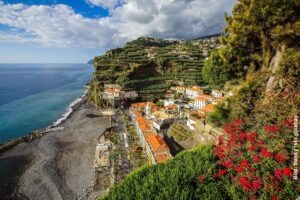Madeira Aktivurlaub: Highlights für Wanderer, Abenteurer & Naturliebhaber 24 Küstenort auf Madeira mit Terrassenfeldern, Atlantikblick und steilen Hängen unter dramatischem Himmel
