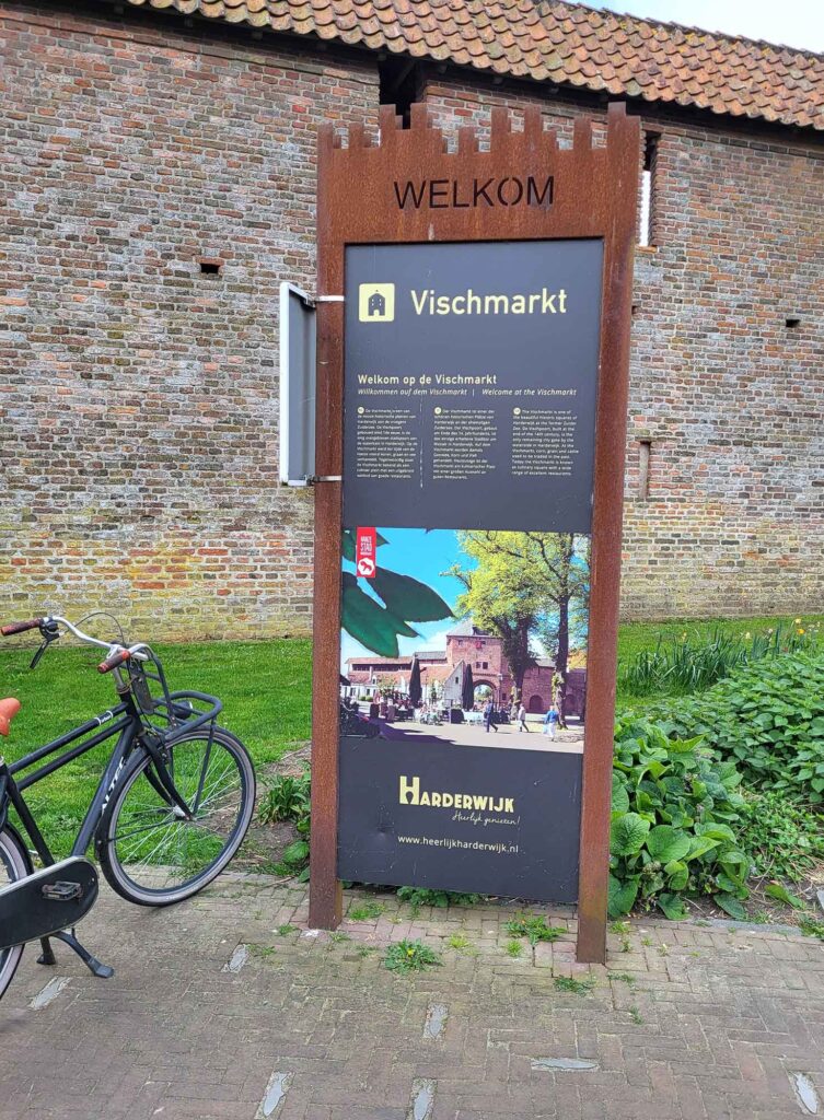 Harderwijk: Entschleunigung zwischen Hansestadt und Veluwemeer 4 Informationsschild zum Vischmarkt vor alter Backsteinmauer in Harderwijk