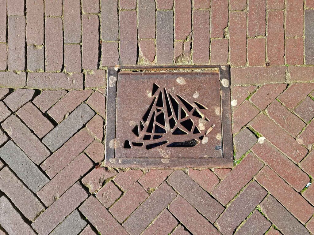 Harderwijk: Entschleunigung zwischen Hansestadt und Veluwemeer 15 Kanaldeckel mit Segelschiffsymbol im Pflaster von Harderwijk