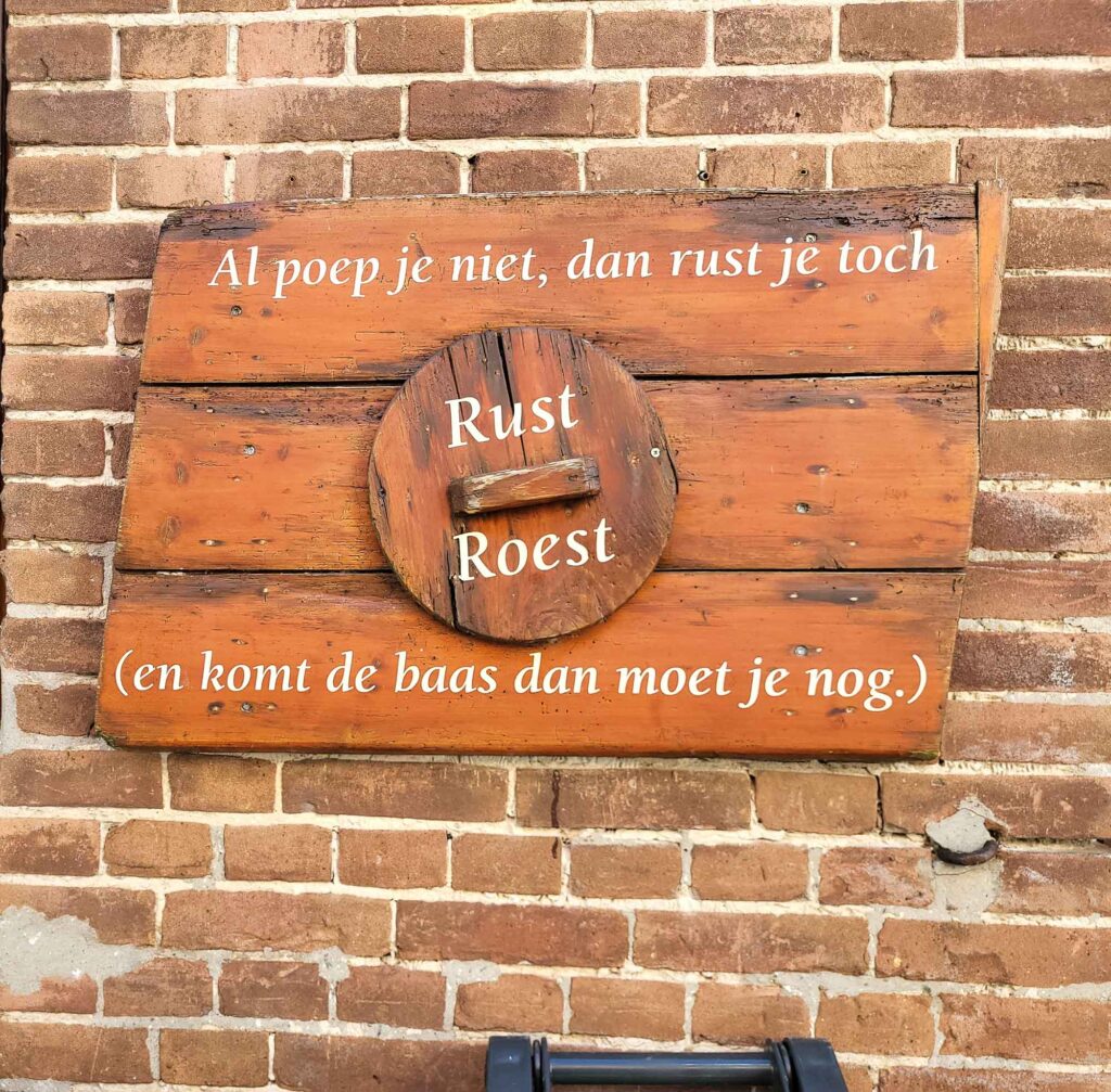 Harderwijk: Entschleunigung zwischen Hansestadt und Veluwemeer 20 Rustikale Holztafel mit niederländischem Spruch an Backsteinmauer in Harderwijk