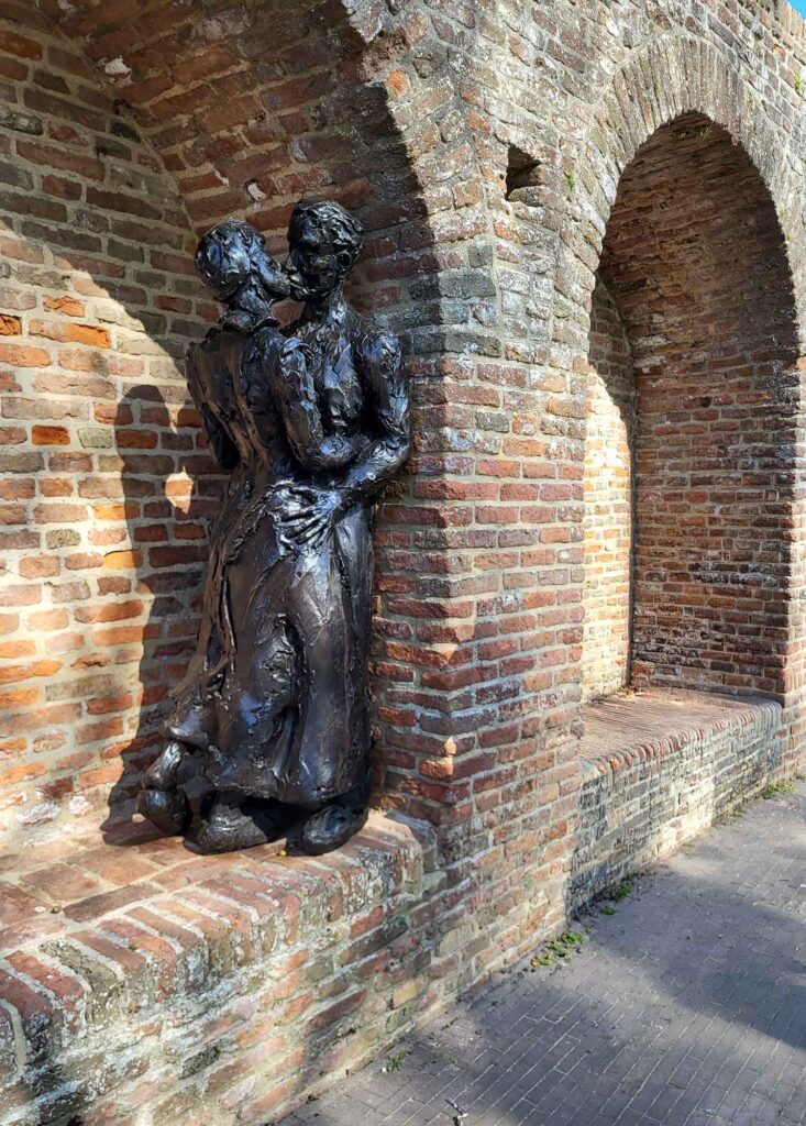 Harderwijk: Entschleunigung zwischen Hansestadt und Veluwemeer 7 Bronzeskulptur eines Paares vor historischer Backsteinmauer in Harderwijk