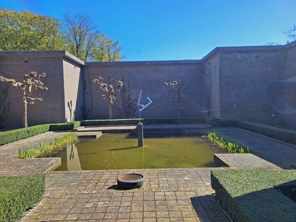 Ruhiger Innenhof mit Wasserbecken, geometrischen Hecken und moderner Skulptur im Kröller-Müller Museum