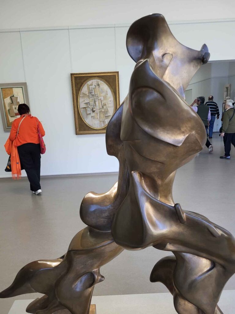 Abstrakte Bronzeskulptur in einem Ausstellungsraum des Kröller-Müller Museums mit Besuchern im Hintergrund
