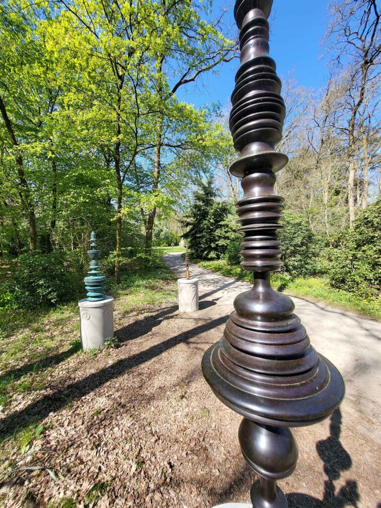 Spazierweg durch den Park mit mehreren modernen Skulpturen auf Sockeln entlang des Weges