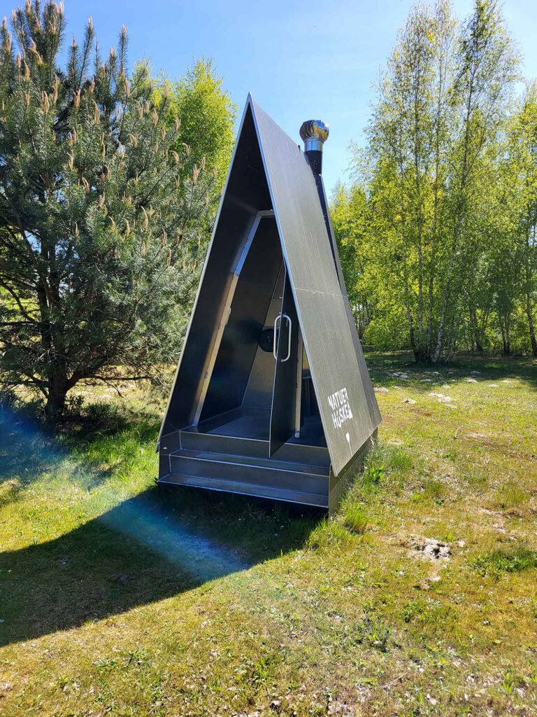 Maritimes Erbe erleben: Eine traditionelle Botterfahrt auf dem Veluwemeer ab Harderwijk 13 Eine moderne, spitz zulaufende A-Frame-Hütte aus Metall auf einer grünen Wiese, die als umweltfreundliche öffentliche Toilette dient.