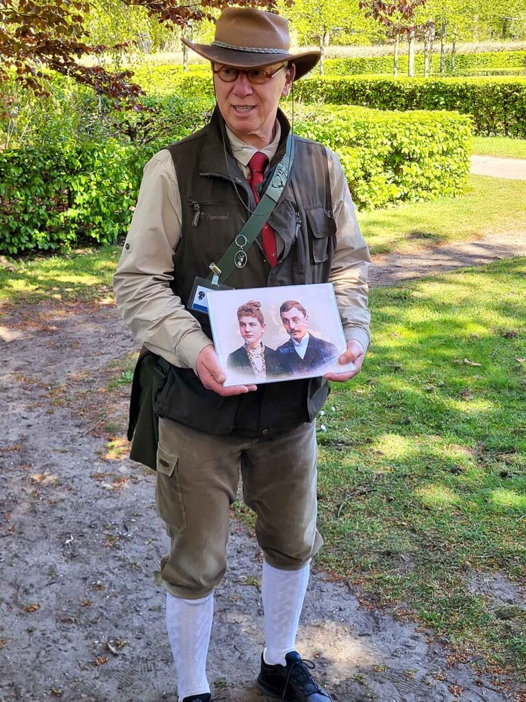Mann in historischer Kleidung zeigt ein altes Foto während einer Führung im Park