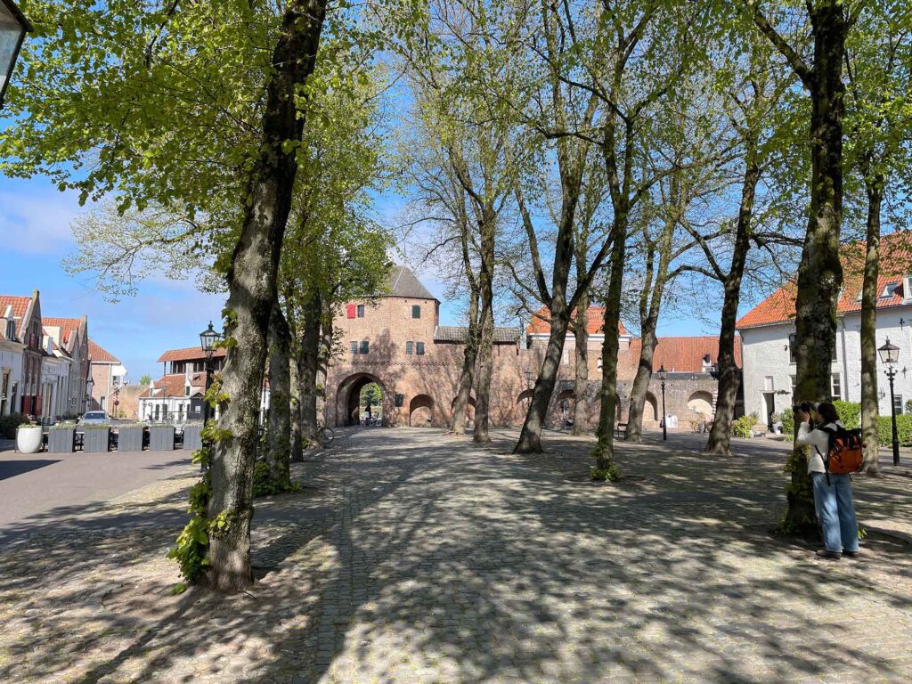 Harderwijk: Entschleunigung zwischen Hansestadt und Veluwemeer 3 Historisches Stadttor Vischpoort in Harderwijk mit Bäumen und Kopfsteinpflaster im Frühling