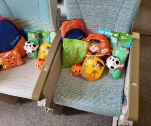 Bunte Emirates-Kinder-Sets mit Spielzeug und Heften auf Flugzeugsitzen im Airbus A380.