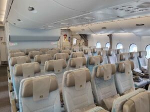 Leere Passagierkabine im Emirates Airbus A380 mit hellblauen Sitzen und Gepäckfächern.