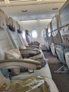 Sitzreihe im Emirates Airbus A380 mit Kissen, Decken, Armlehnen und Bordbildschirmen.