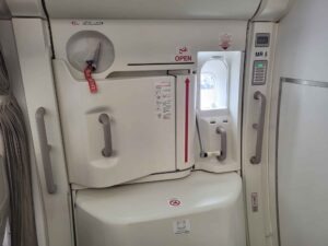 Notausgangstür im Emirates Airbus A380 mit Griffen, Sicherheitsaufklebern und roter Öffnungsmarkierung.