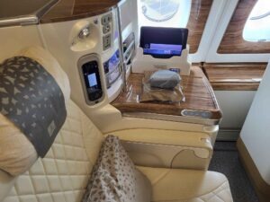 Business-Class-Sitz im Emirates Airbus A380 mit Tisch, Bildschirm, Sitzsteuerung und Holzdekor.