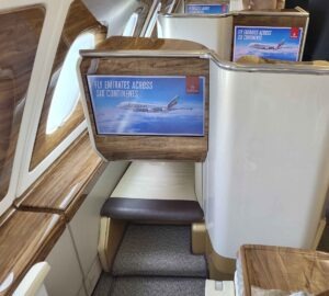 Emirates A380 Business Class mit Einzelsitzen, Bordmonitoren, Holzdekor und Kabinenfenstern.