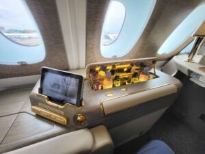 Emirates First-Class-Suite im Airbus A380 mit Minibar, Tablet, Holzdekor und goldfarbenen Details.