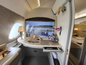 Private Emirates First-Class-Suite im A380 mit Bildschirm, Spiegel, Lampe, Ablage und Snackkorb.