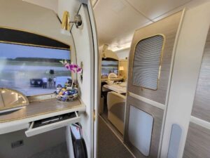 Gang in der Emirates First Class im Airbus A380 mit privaten Suiten, Türen und goldfarbenen Details.