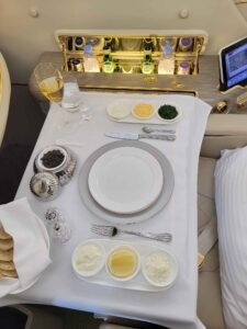 First-Class-Tisch im Emirates A380 mit Kaviarservice, Gläsern, Besteck und beleuchteter Minibar.