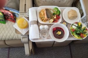 Serviertes Bordmenü im Emirates Airbus A380 mit Fisch, Reis, Gemüse, Salat, Dessert und Getränk.