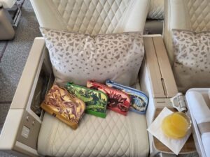 Mehrere farbige Emirates Amenity Kits auf einem hellen Sitz im Airbus A380.