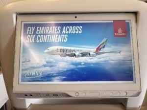 Bordmonitor im Emirates Airbus A380 mit Werbemotiv eines A380 und dem Text Fly Emirates Across Six Continents.