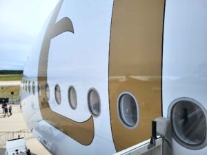 Nahaufnahme des Emirates-Schriftzugs am Rumpf eines Airbus A380 mit mehreren Kabinenfenstern.