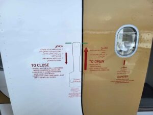 Einstiegstür eines Emirates Airbus A380 mit Hinweisen zum Öffnen und Schließen der Flugzeugtür.