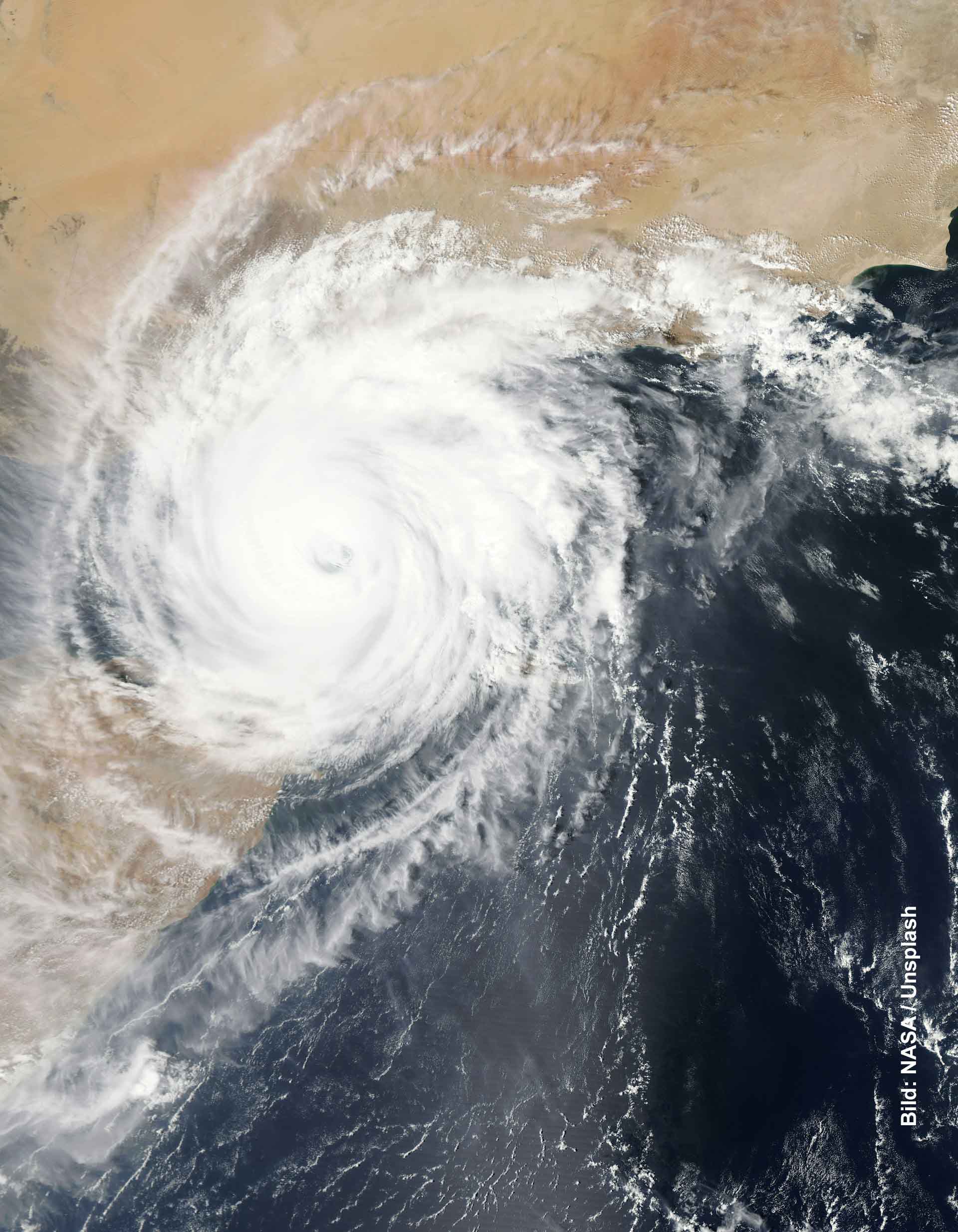 Satellitenbild eines großen tropischen Wirbelsturms über dem Meer nahe einer Küstenregion.