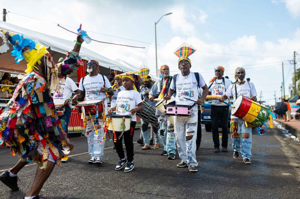Trommler und Tänzer in farbenfrohen Kostümen bei der Parade of the Bands auf Saint Lucia.
