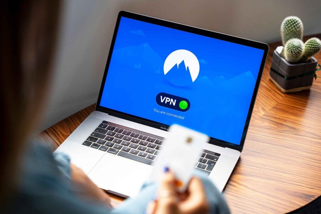 Person sitzt vor einem Laptop, auf dessen Bildschirm eine aktive VPN-Verbindung angezeigt wird.