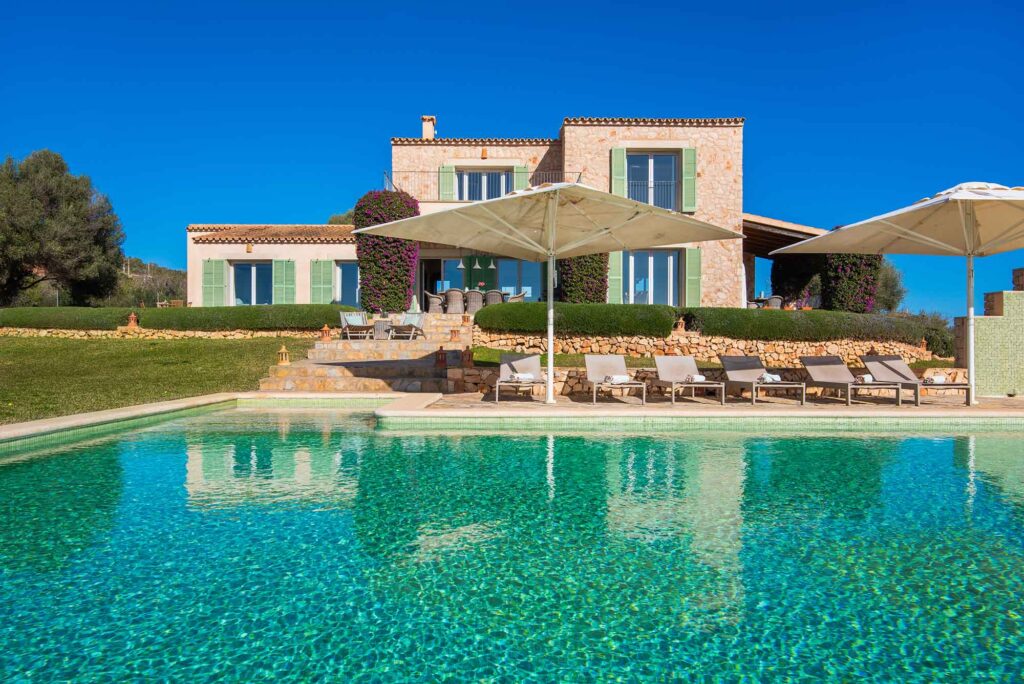 Fincaurlaub auf Mallorca: Worauf es ankommt 4 Finca Taraluna auf Mallorca mit großem Swimmingpool, Sonnenschirmen, Liegestühlen und Natursteinfassade
