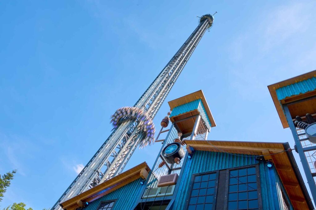 Ein Sommertag im Bayern-Park: Wasserspaß, Achterbahnen und Geduld beim Anstehen 3 Freifallturm Voltrum mit schnell abwärtsfahrender Gondel vor blauem Himmel im Bayern-Park