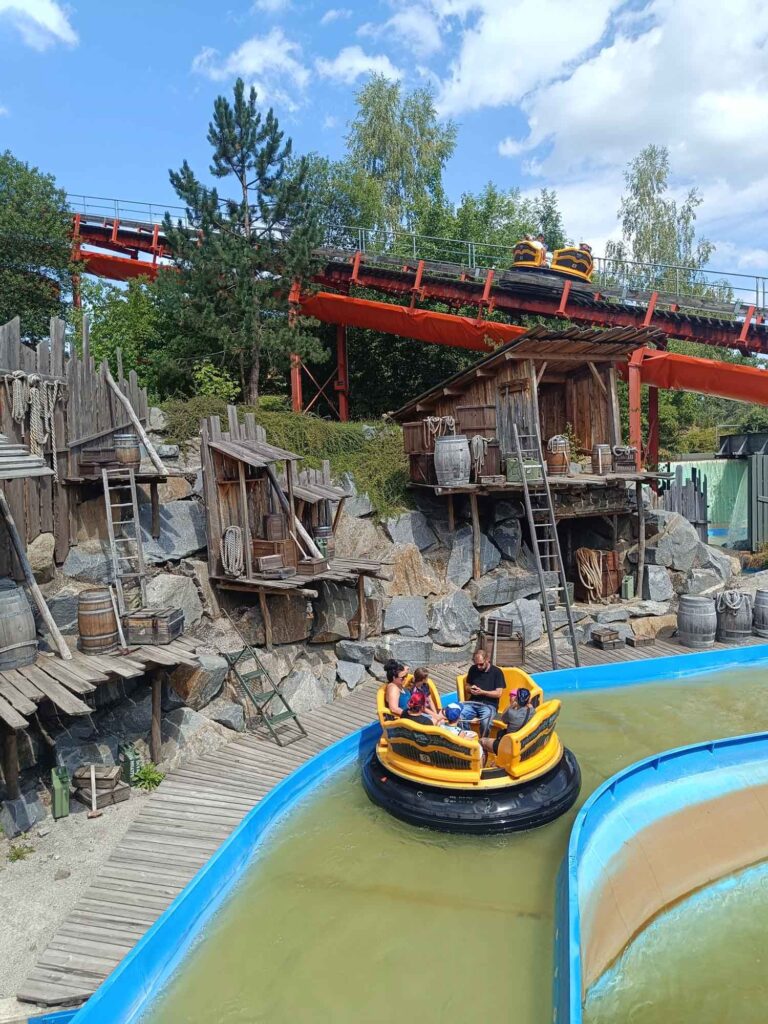 Ein Sommertag im Bayern-Park: Wasserspaß, Achterbahnen und Geduld beim Anstehen 9 Gelbes Rundboot im Wildwasser-Rafting vor einer Bergwerkskulisse im Bayern-Park