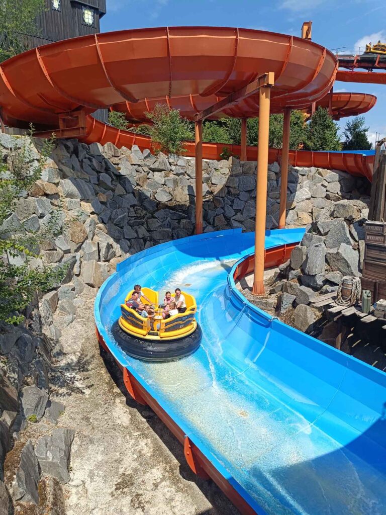 Ein Sommertag im Bayern-Park: Wasserspaß, Achterbahnen und Geduld beim Anstehen 8 Familie in einem gelben Rundboot auf der Abfahrt des Wildwasser-Raftings