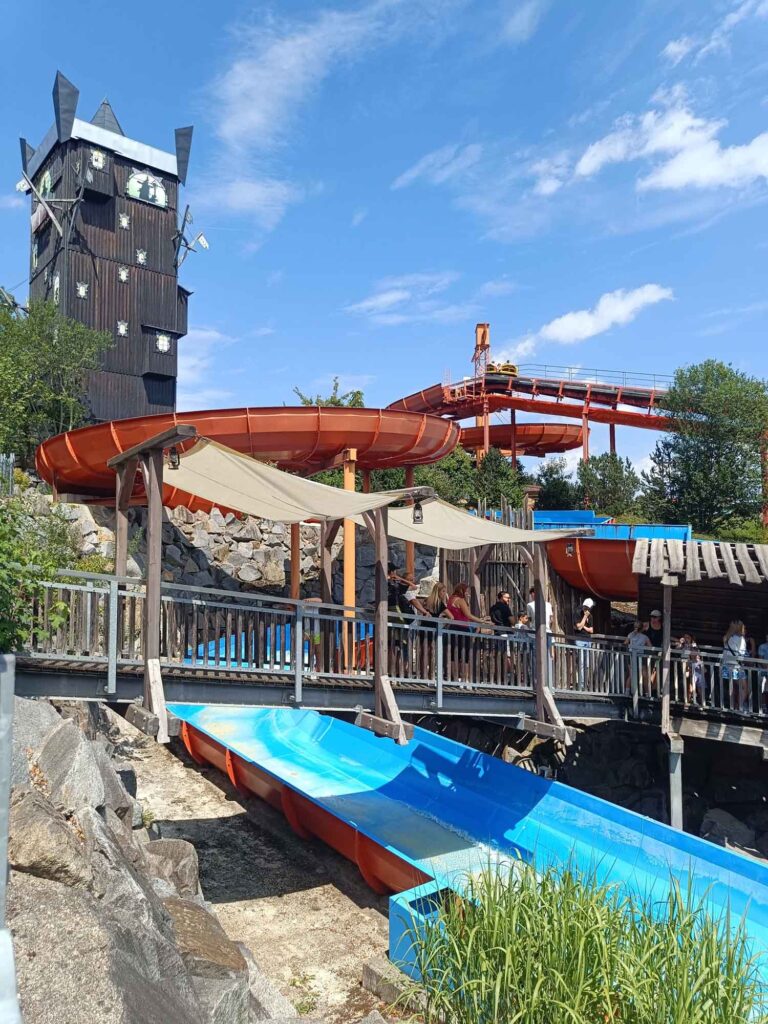 Ein Sommertag im Bayern-Park: Wasserspaß, Achterbahnen und Geduld beim Anstehen 7 Übersicht der Wildwasser-Rafting-Anlage mit Fahrkanälen, Holzstegen und Holzturm