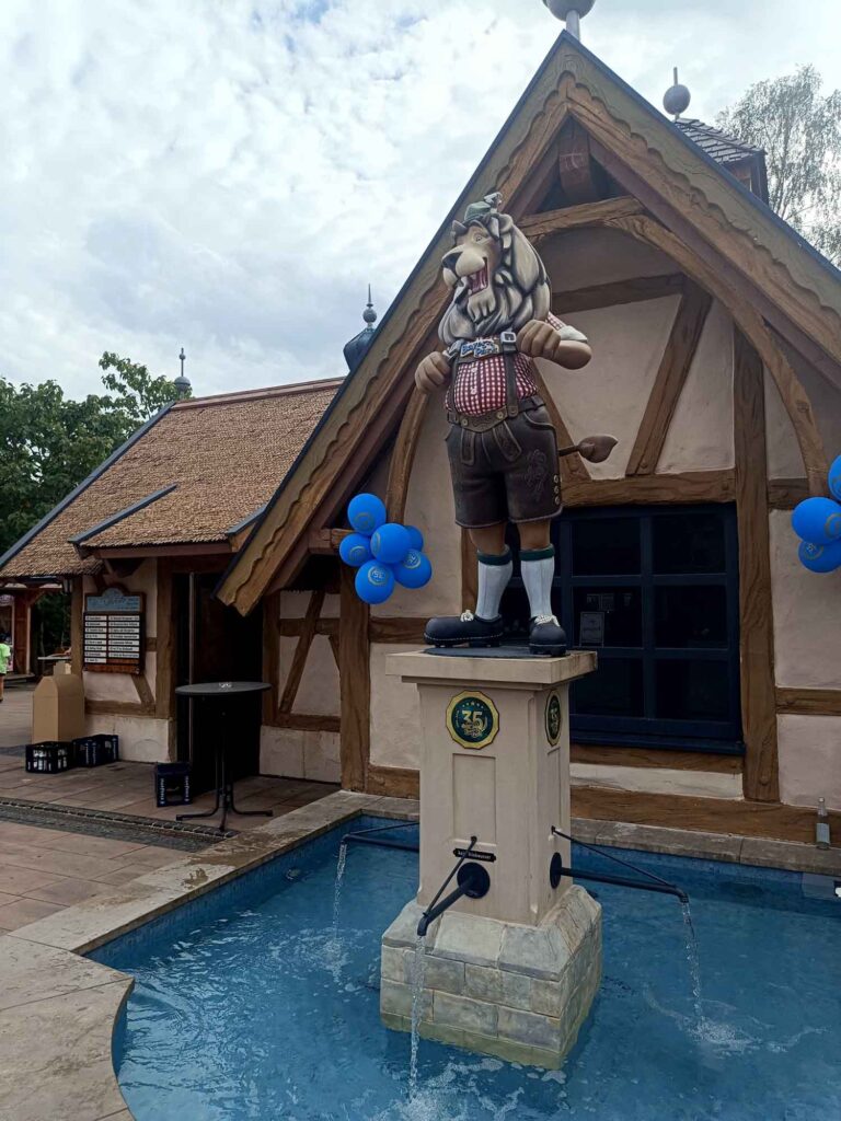 Ein Sommertag im Bayern-Park: Wasserspaß, Achterbahnen und Geduld beim Anstehen 15 Löwenfigur Franz-Xaver auf einem Brunnen mit Emblem zum 35-jährigen Bayern-Park-Jubiläum