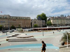 Lausanne: Radsport, Hitze und Erbauung 16 Großer gepflasterter und asphaltierter Platz in Lausanne mit Gebäuden und einer Kirche im Hintergrund.