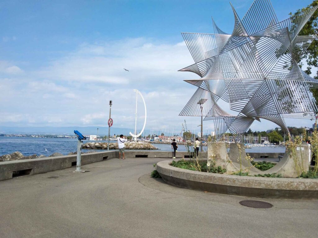 Radsport, Hitze und Erbauung 3 Ruhige Uferpromenade in Lausanne-Ouchy mit Metallskulptur, Hafen und Genfersee am Morgen.