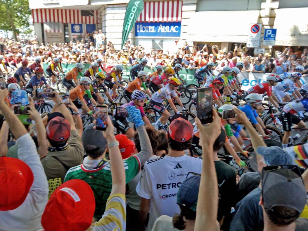 Radsport, Hitze und Erbauung 8 Peloton der Tour de France Femmes fährt beim Start durch eine von Zuschauern gesäumte Straße in Lausanne.