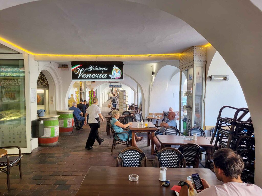 Wasserburg am Inn: Bayerische Bilderbuchstadt in der Innschleife 11 Historischer Laubengang in Wasserburg am Inn mit Café-Tischen, Gelateria und Geschäften unter weißen Gewölben.