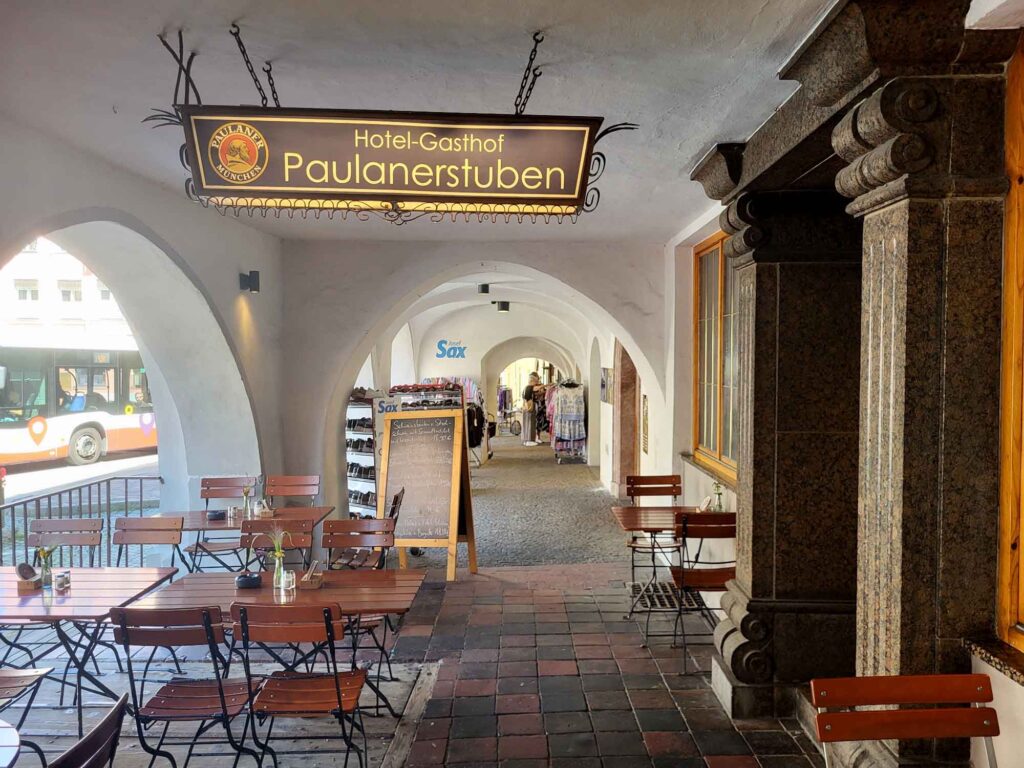 Wasserburg am Inn: Bayerische Bilderbuchstadt in der Innschleife 8 Weiße Arkaden in Wasserburg am Inn mit Tischen und Stühlen vor dem Hotel-Gasthof Paulanerstuben.