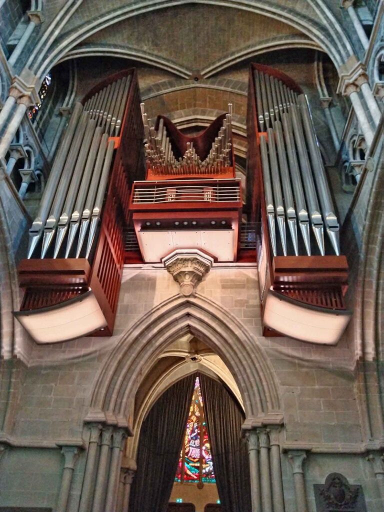 Große Orgel mit zahlreichen silberfarbenen Pfeifen über einem gotischen Bogen in der Kathedrale von Lausanne.