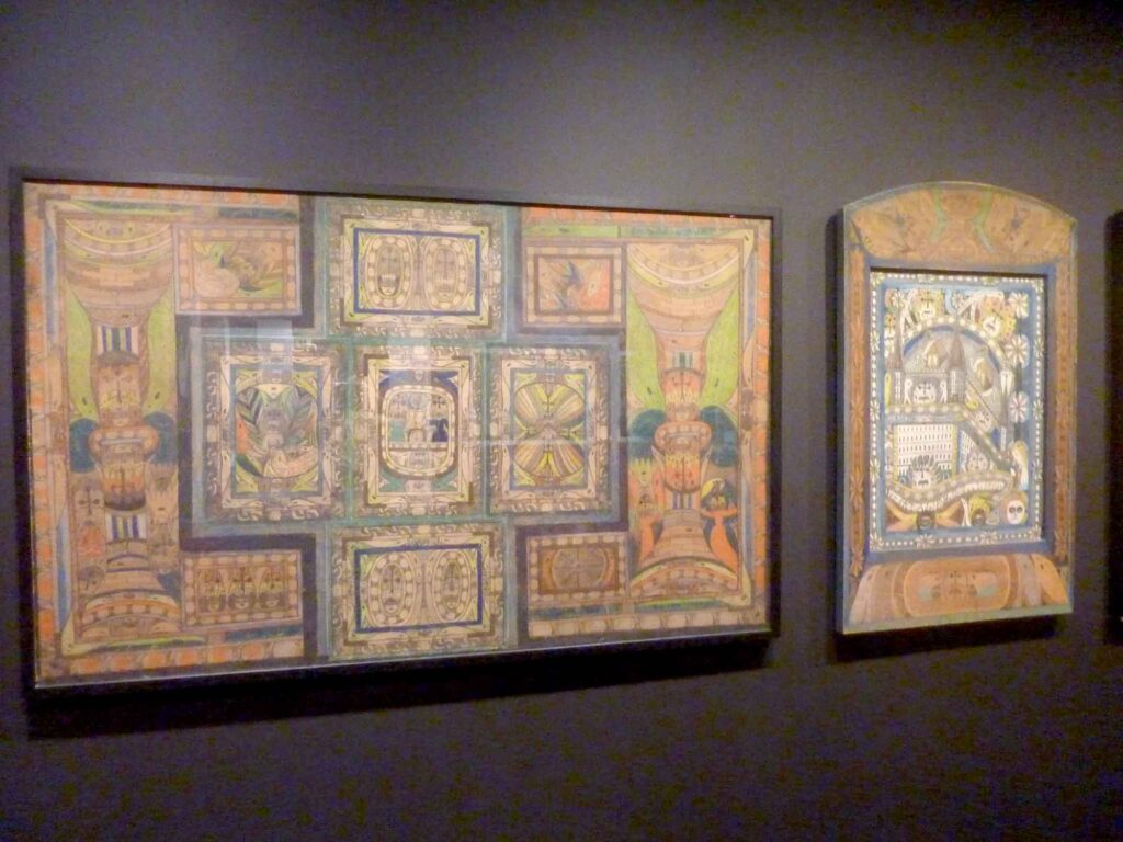 Zwei gerahmte, detailreiche Zeichnungen von Adolf Wölfli an einer dunklen Museumswand.