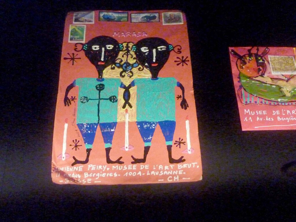 Zwei farbig bemalte und beschriftete Briefumschläge von Chris Besser mit Figuren und Briefmarken.