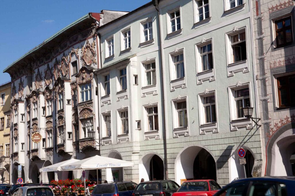 Wasserburg am Inn: Bayerische Bilderbuchstadt in der Innschleife 4 Straßenseite am Marienplatz in Wasserburg am Inn mit bunt verzierten Fassaden, Erkern und Sonnenschirmen der Außengastronomie.