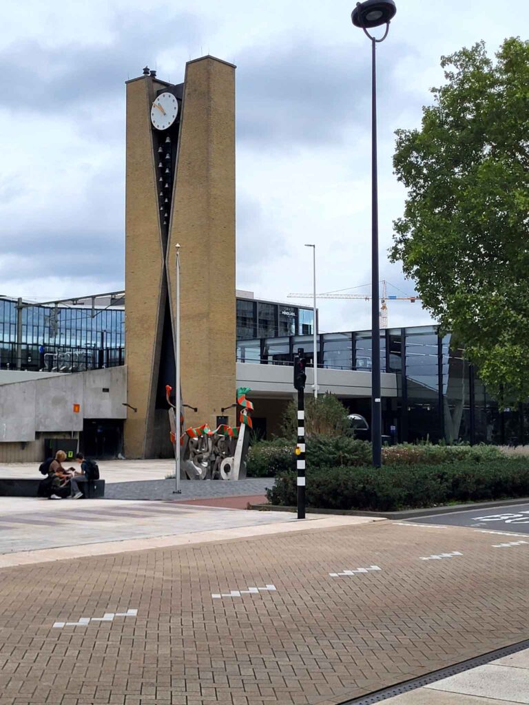 Tilburg: Wo Industriekultur auf Design und neue Ideen trifft 5 Hoher Backstein-Uhrturm De Wasknijper mit Glocken am Bahnhof Tilburg Centraal.