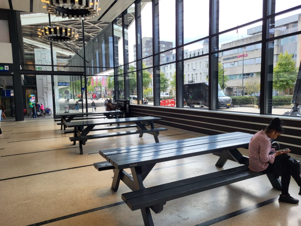 Tilburg: Wo Industriekultur auf Design und neue Ideen trifft 3 Heller Wartebereich im Bahnhof Tilburg Centraal mit langen dunklen Tischen und großen Fenstern.