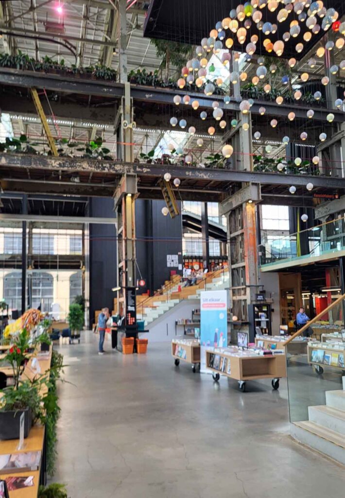 Tilburg: Wo Industriekultur auf Design und neue Ideen trifft 12 Innenraum der LocHal in Tilburg mit historischen Stahlträgern, Bücherregalen, Treppen und hängenden Leuchten.