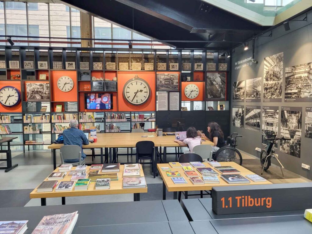 Tilburg: Wo Industriekultur auf Design und neue Ideen trifft 14 Ausstellungsbereich in der LocHal mit mehreren historischen Bahnhofsuhren, Fotos und Dokumenten.