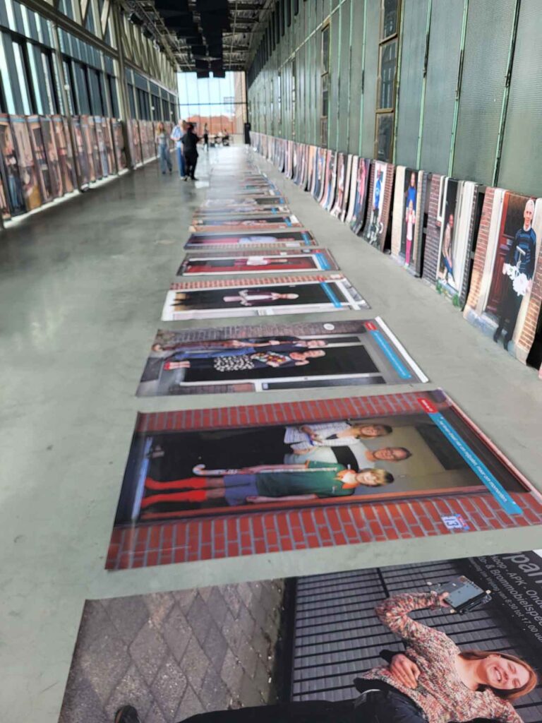 Tilburg: Wo Industriekultur auf Design und neue Ideen trifft 17 Reihe großformatiger Porträtfotografien der Ausstellung „Geluk op 13“ in einem Gang der LocHal.